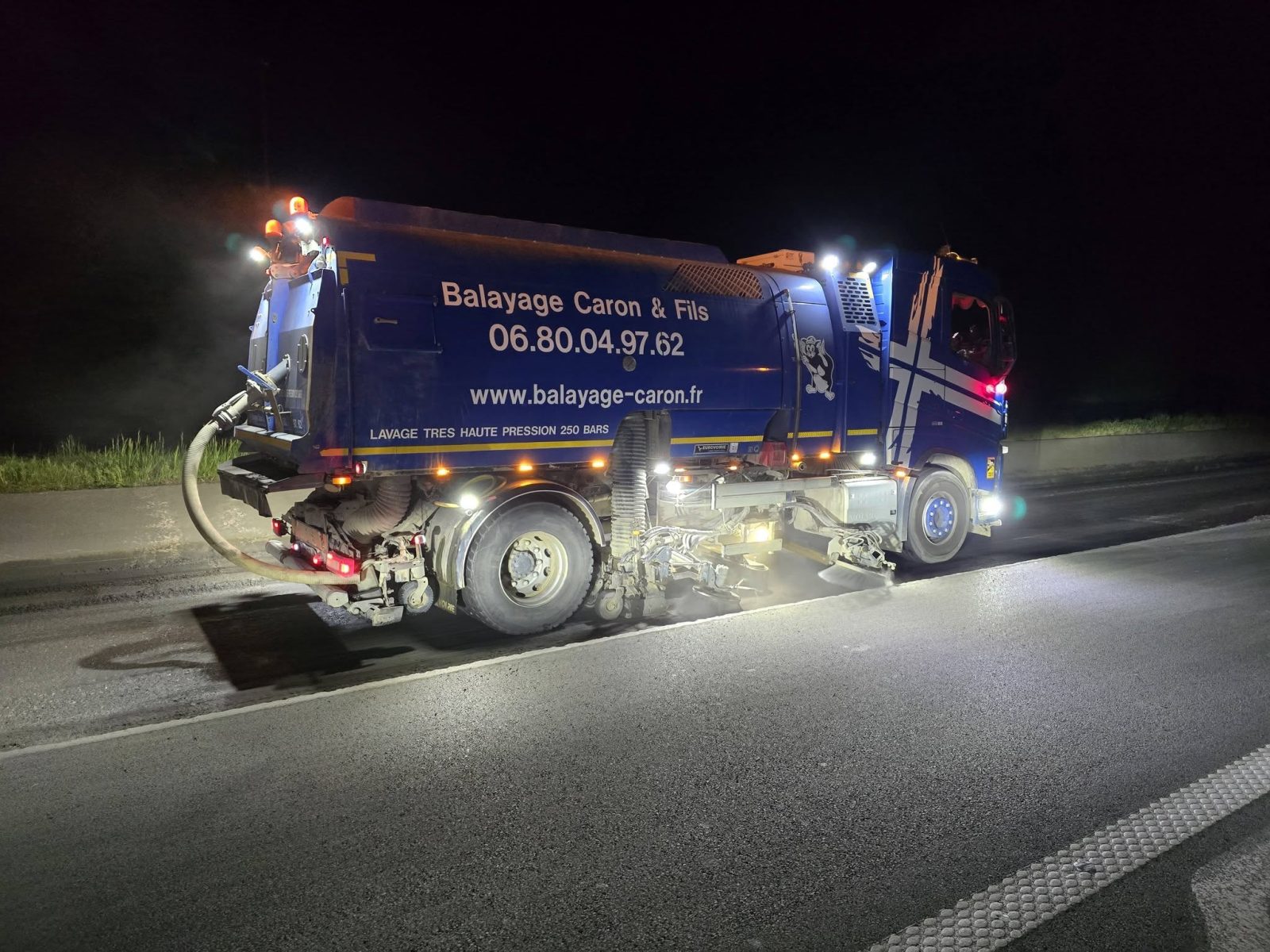 Balayage phasé jour et nuit sur la jonction A22 RN356 à Lille : balayeuse Caron et Fils brosses baissées de nuit sous projecteurs après le grattage du macadam