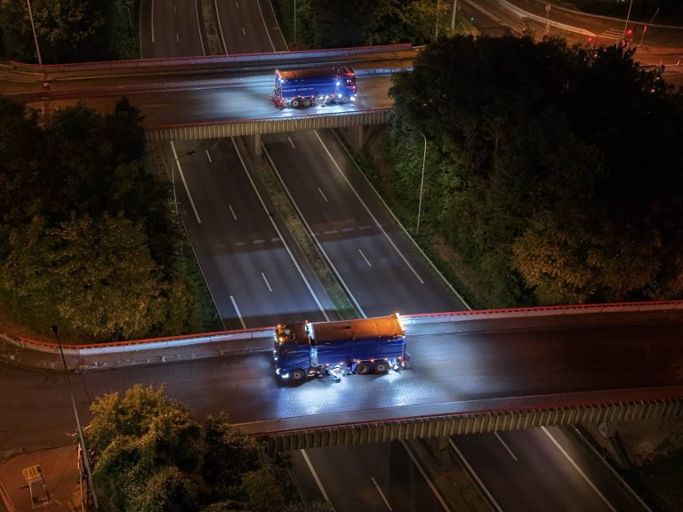 Balayeuse Caron & Fils sur porteur Scania Super bleu à trois essieux, stationnée sur une plateforme portuaire de Calais