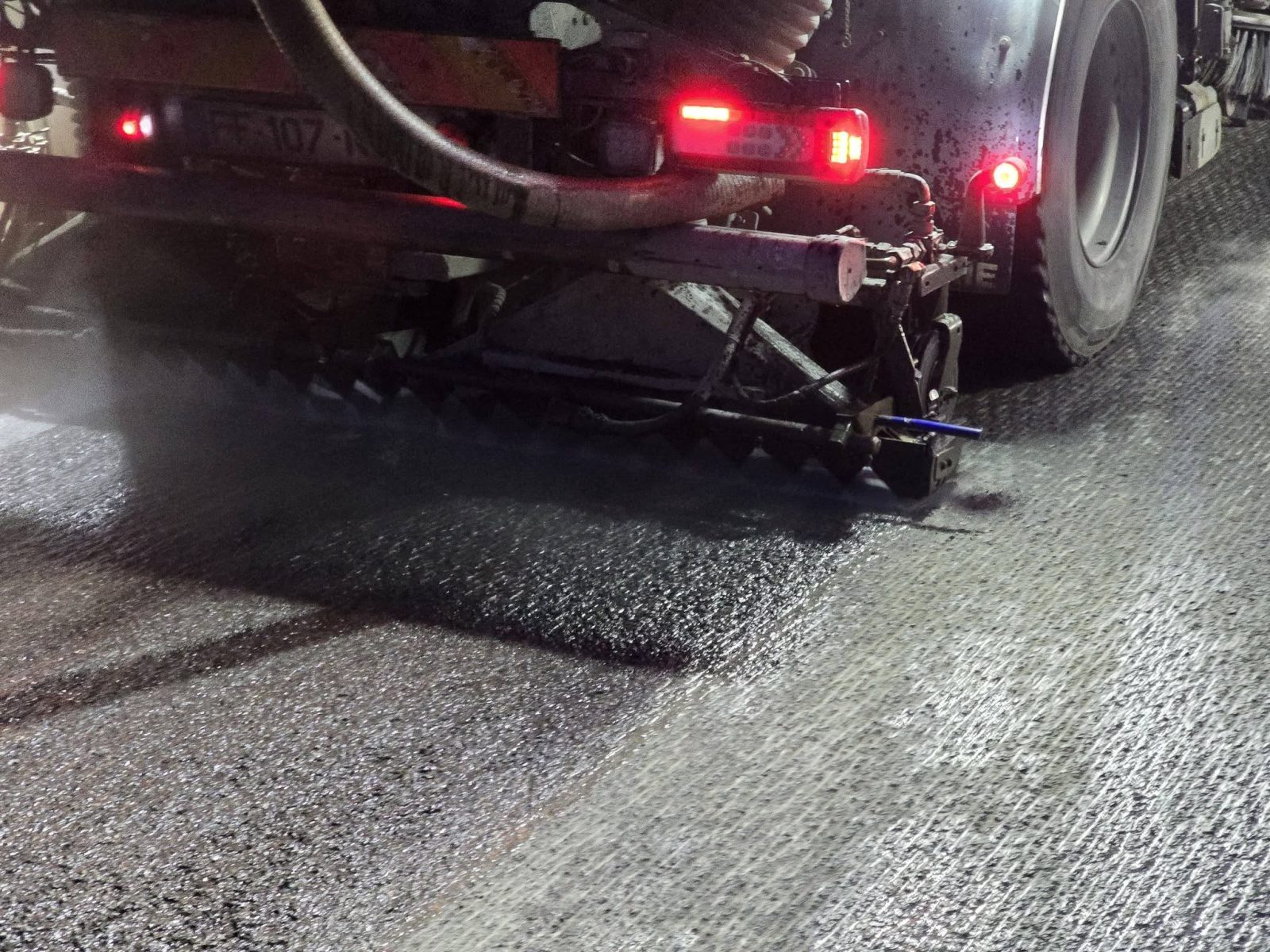 Rampes de lavage très haute pression projetant l'eau à 300 bars sur l'asphalte raboté de la RN 41, de nuit